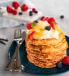 Ein Stapel Pancakes, garniert mit Waldfrüchten und Minze, darüber Honig – mit Kaba Vanille